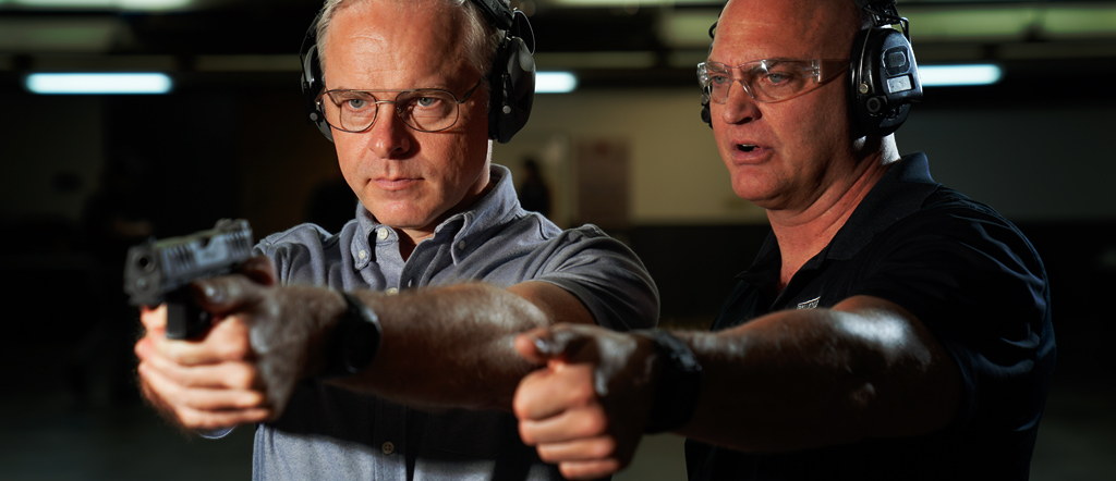 One man teaching another how to shoot a firearm