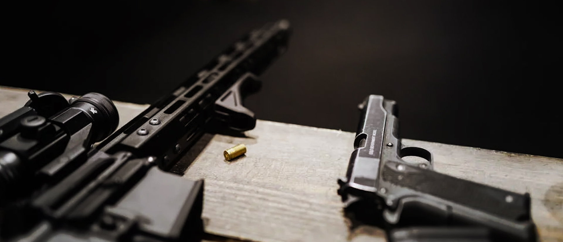 Carbine and handgun laying on bench