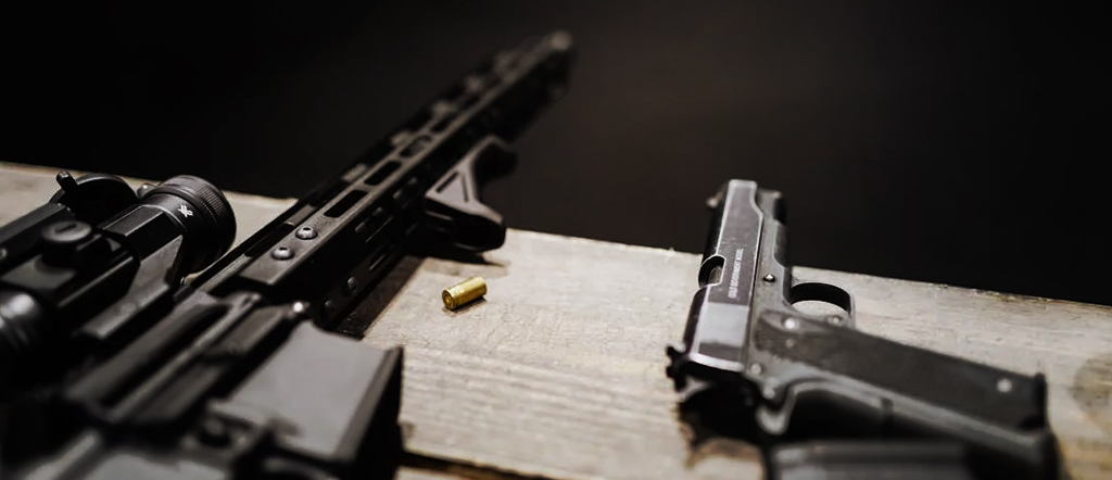Carbine and handgun laying on bench